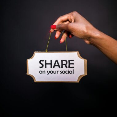 A hand holds a sign reading 'Share on your social' against a dark background.