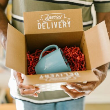 Man holding a box with a special delivery coffee mug inside.